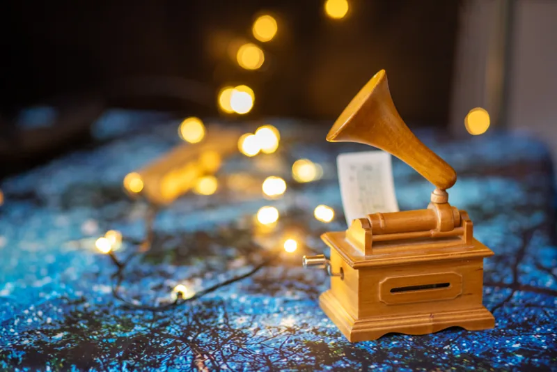 Un gramophone miniature posé sur le tissu bleu scintillant du décor.
