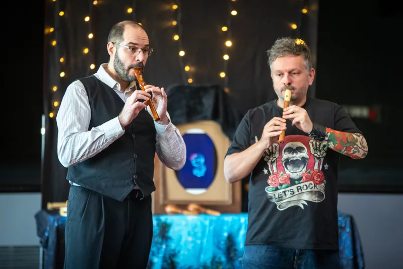 Les deux artistes jouent de petits instruments à vent.